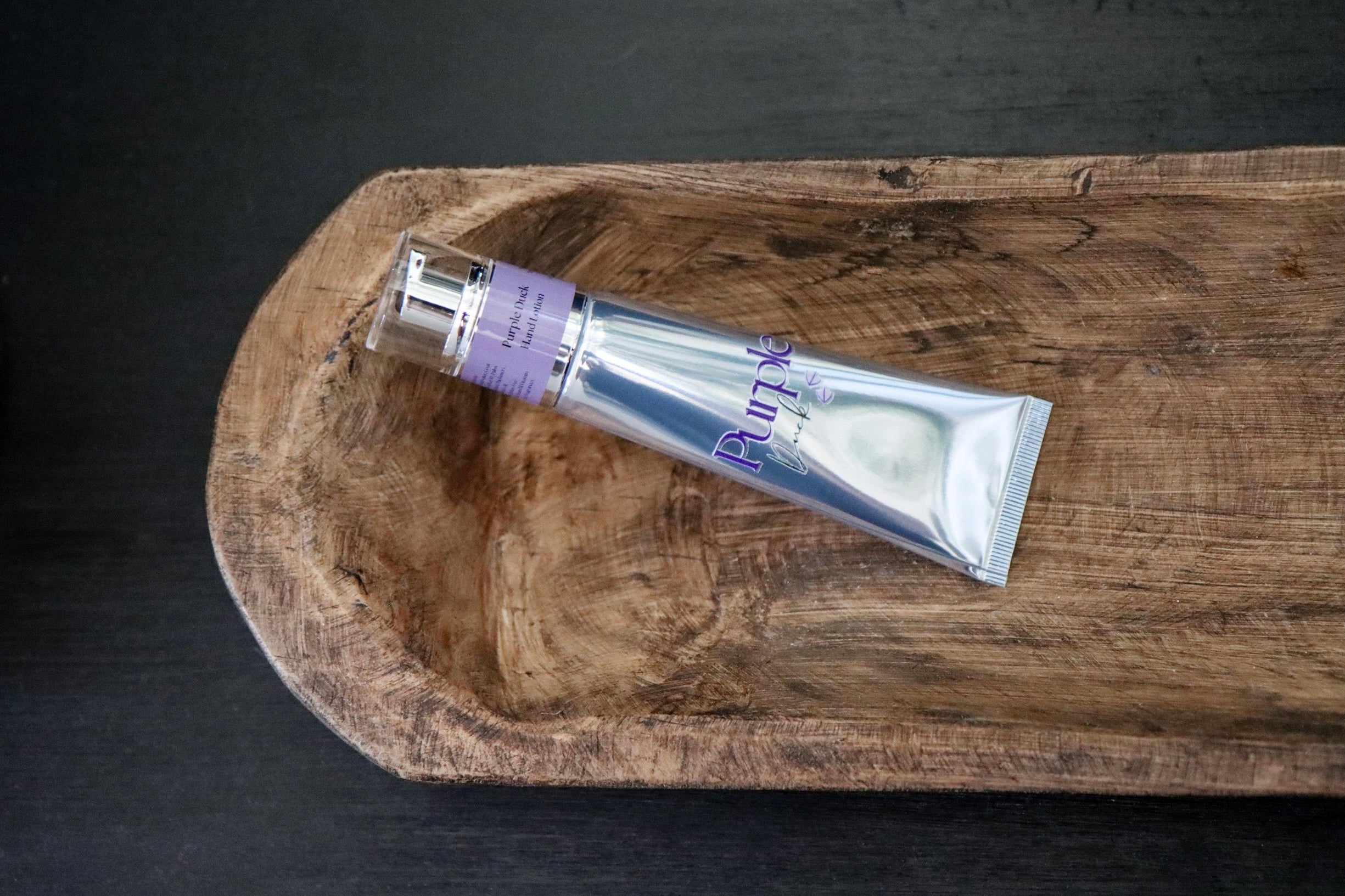 Goats Milk Hand Lotion on a wooden tray against a dark background