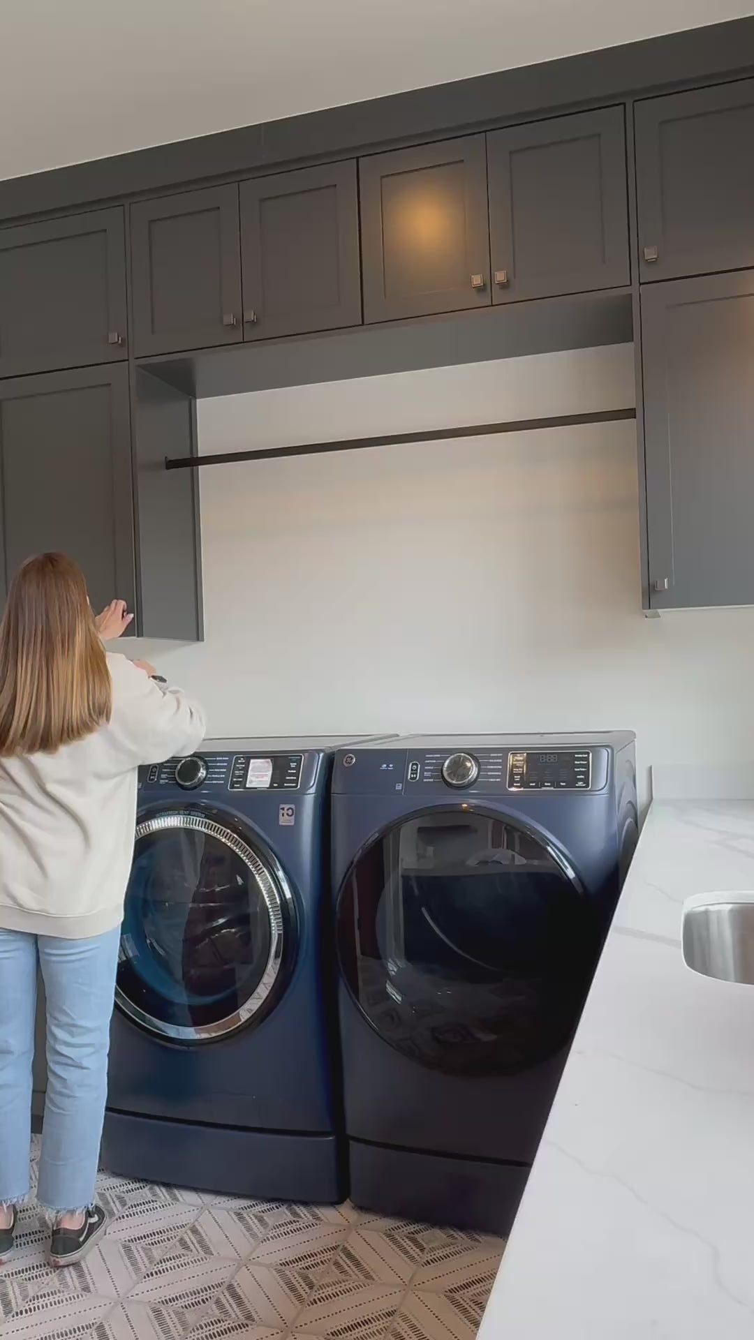 Load video: Girl standing in front of two front-loading washing machines, appearing to do laundry.